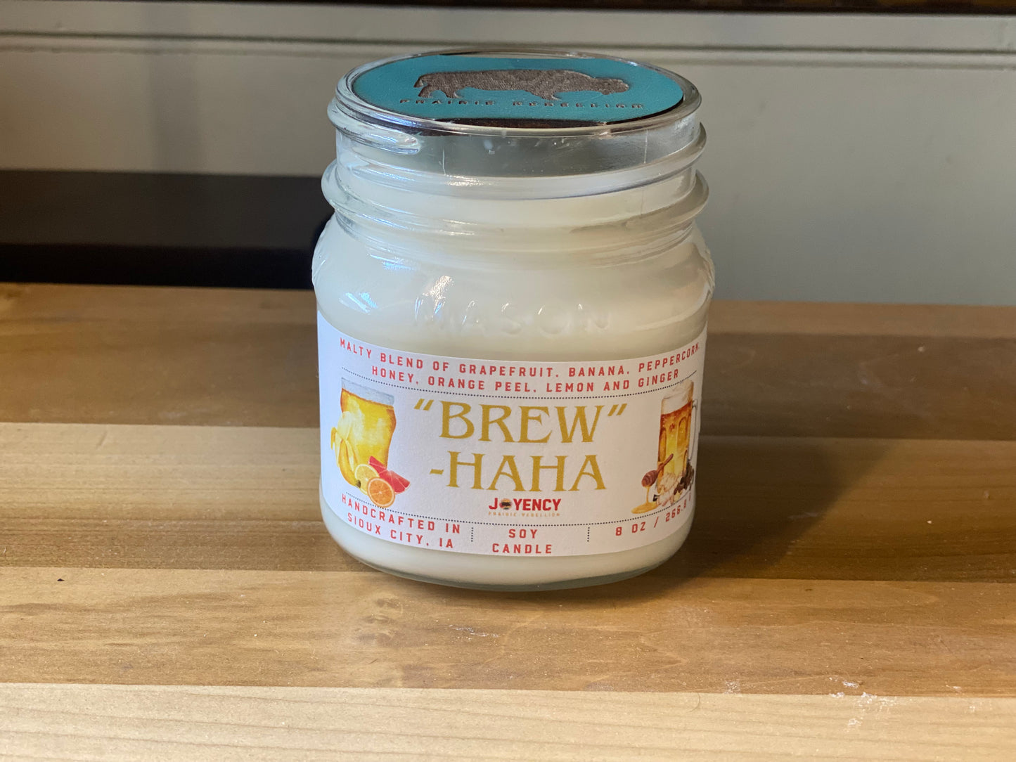 Brew-HaHa candle styled on table with citrus and spice accents
