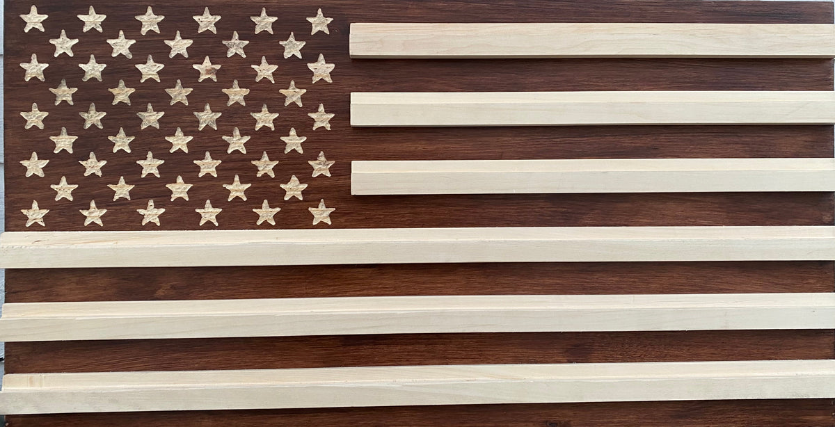 Wooden American flag with brown and beige stripes against a light blue wall.