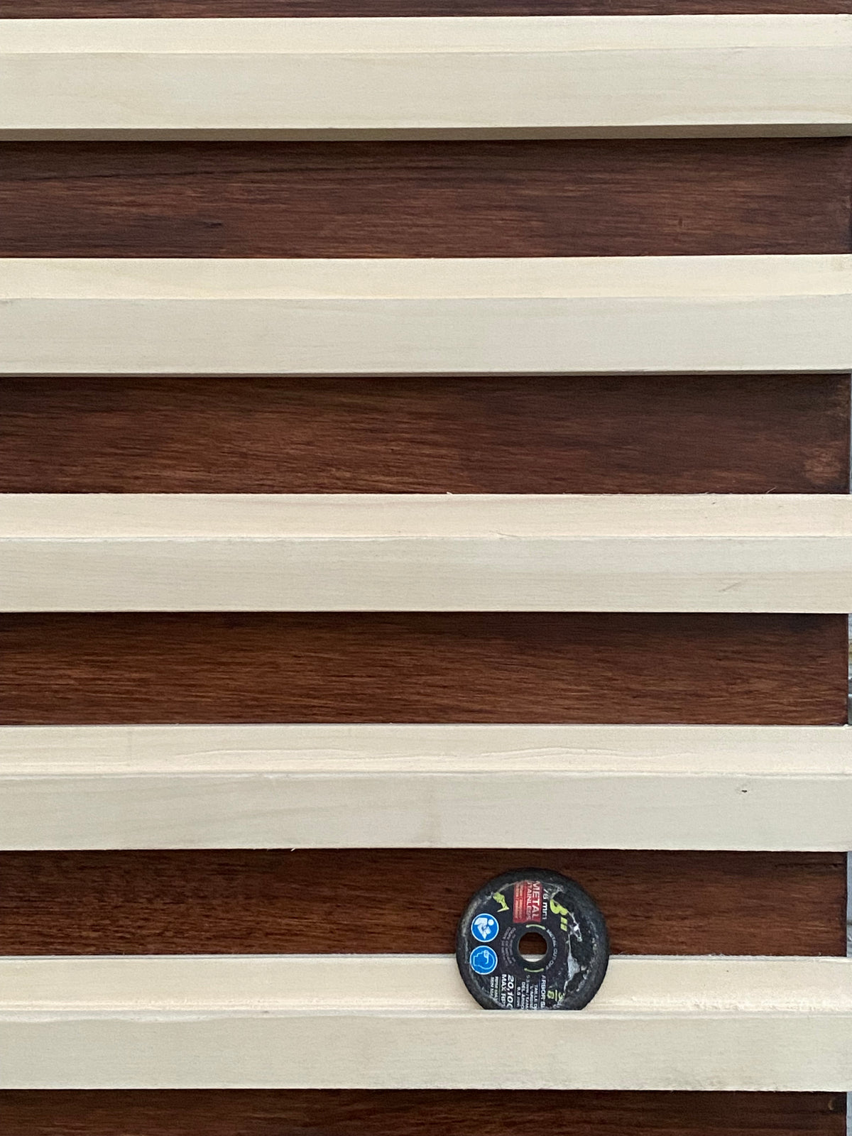 Close-up of wooden paneling with a circular object on a striped background