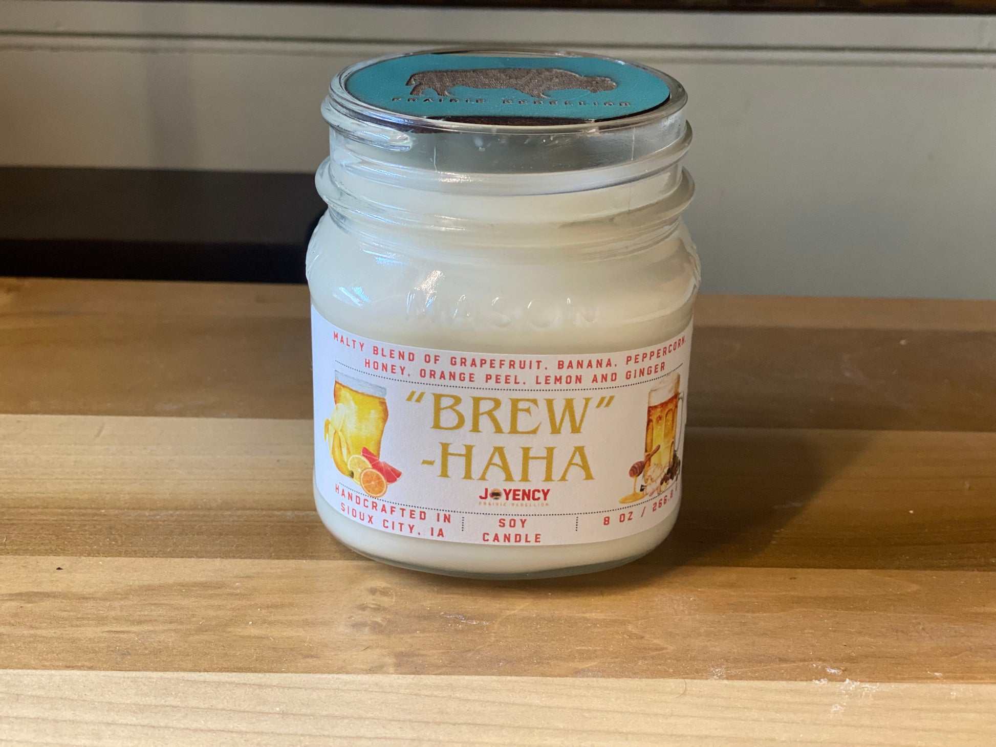 Brew-HaHa candle styled on table with citrus and spice accents