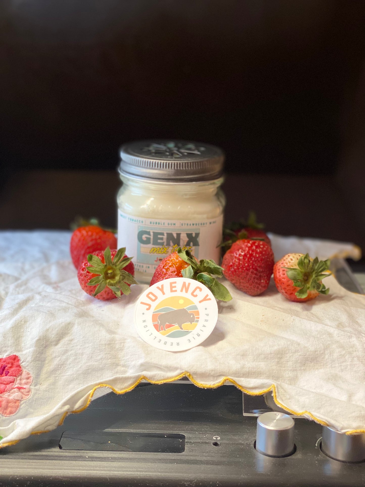 Jar of 'GEN.X' on a table with strawberries and a visible brand logo.