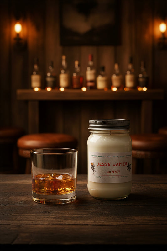Jesse James whiskey and tobacco soy candle with whiskey glass in rustic bar setting