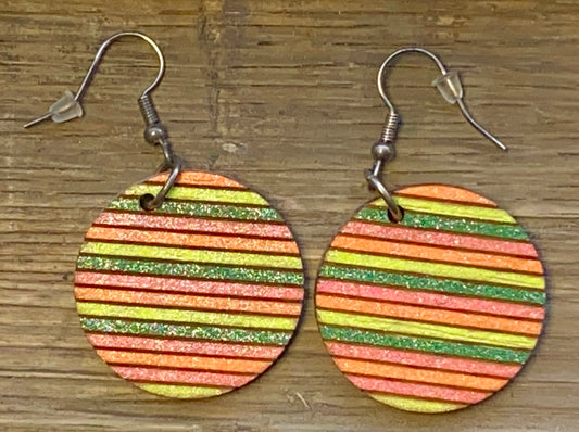 A pair of wooden multicolor circle earrings with a striped pattern on a wooden surface.