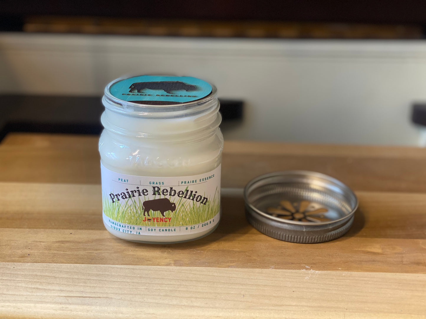 Prairie Rebellion hand-poured soy wax candle with prairie grass background