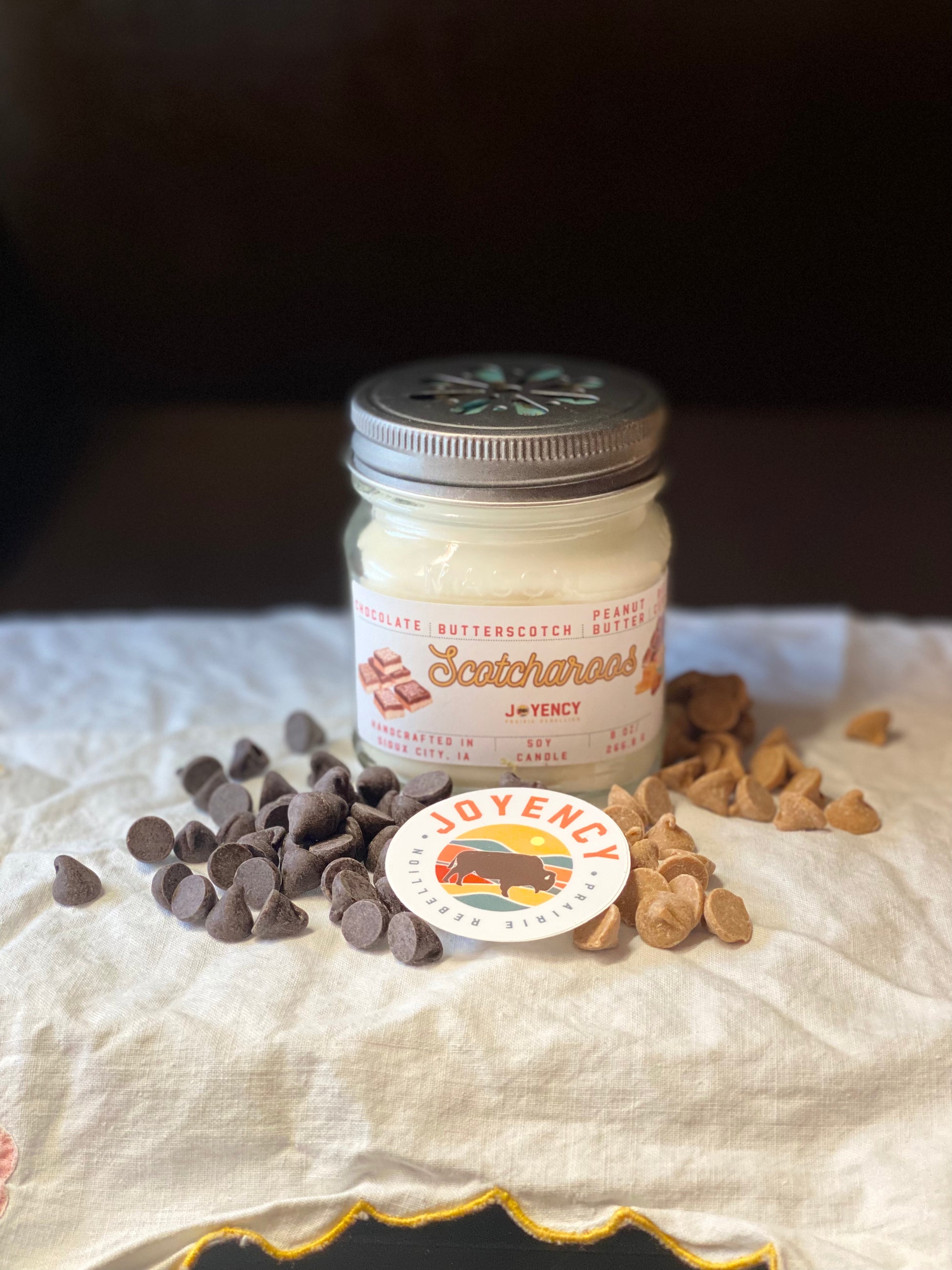 Jar of fudge with chocolate chips and a teddy bear on a white surface