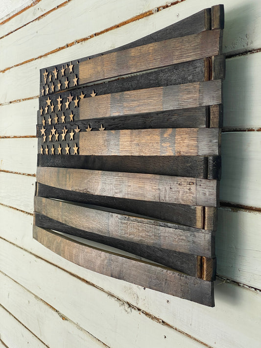 A rustic wooden American flag wall art piece made from reclaimed wood planks, mounted on a white painted wood plank wall.